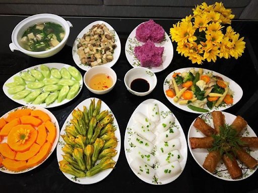 Mâm cỗ gồm 9 món:1. Xôi lá cẩm tím, 2. Chả giò chay, 3. Bánh hỏi, 4. Bông bí nhồi đậu hấp hũ, 5. Đậu non sốt nấm rơm, 6. Rau xào thập cẩm, 7. Salad dưa leo, 8. Canh đậu hũ hẹ, 9. Đu đủ (Ảnh eva.vn).