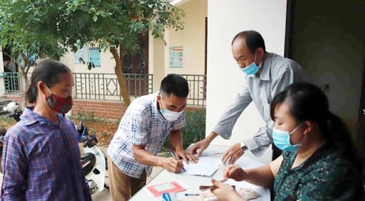 Chi trả tiền hỗ trợ cho hộ nghèo. Ảnh TTXVN.