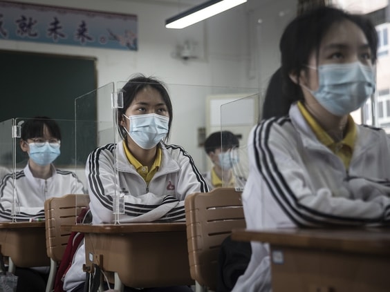 Các học sinh ở Vũ Hán ngồi sau các lồng kính được thiết kế riêng tại từng bàn. Ảnh: AFP
