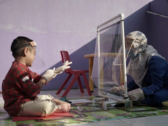Một tấm màng nhựa được đặt giữa giáo viên và học sinh ở Semarang. Ảnh: Reuters