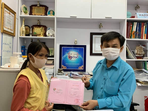 Ông Lê Minh Hiển - trưởng phòng công tác xã hội Bệnh viện Chợ Rẫy - trao thư cảm ơn của đơn vị cho chị Bùi Thị Ngọc Tuổi (vợ anh Tâm). Ảnh: BVCC.