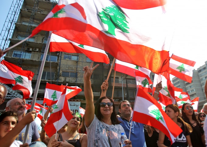 Người biểu tình Lebanon giương cao quốc kỳ trước một rào chắn tạm được dựng trên một con đường chính ở khu vực Jal el-Dib, phía bắc thủ đô Beirut vào ngày 21 tháng 10 năm 2019. Ảnh: Getty