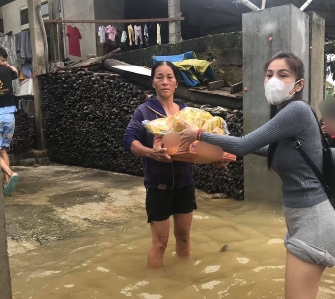 Nữ ca sĩ Thủy Tiên không e ngại mà lội giữa dòng nước đưa từng thùng mì. (Ảnh: FBNV)