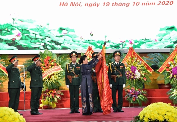 Chủ tịch Quốc hội Nguyễn Thị Kim Ngân gắn Huân chương Độc lập hạng Ba lên lá cờ truyền thống của Báo Quân đội nhân dân. Ảnh: ĐBND