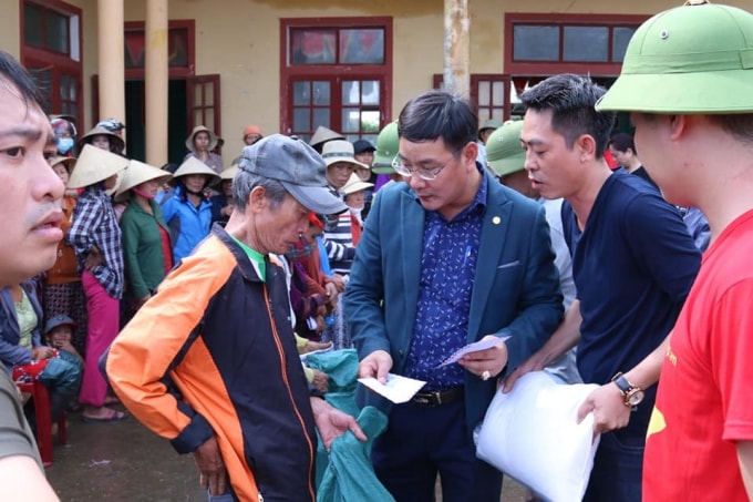 Ông Nguyễn Ngọc Quyết (ở giữa) - Tổng Biên tập Tạp chí điện tử Hòa Nhập trao quà cứu trợ cho bà con nhân dân vùng lũ thôn Phú Hòa, xã Phú Thuỷ, huyện Lệ Thuỷ, Quảng Bình