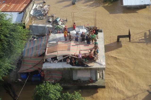 Nhiều người dân ở Cagayan đứng trên nóc nhà đợi lực lượng cứu hộ Phillipines giải cứu khỏi lũ lụt - Ảnh: Reuters