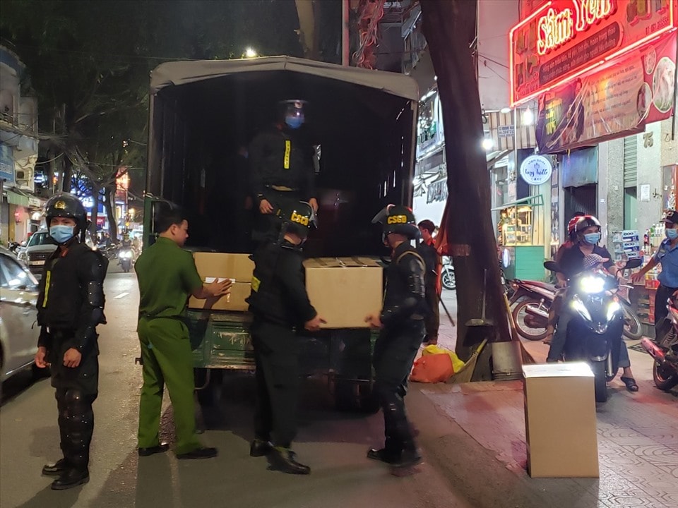 Lực lượng chức năng vận chuyển các thùng thuốc tây bị tạm giữ ra xe công vụ, phục vụ công tác điều tra. Ảnh: laodong.vn