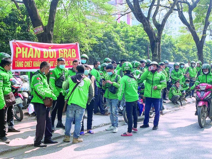 Hàng trăm tài xế đồng loạt căng băng rôn, tắt ứng dụng (app) phản đối việc Grab tăng giá cước và mức chiết khấu.