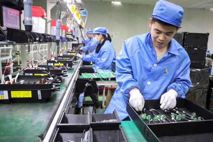 Các nhân viên làm việc trên các sản phẩm quang điện tại một công ty năng lượng tái tạo ở Tonglu, Trung Quốc, hôm thứ Tư. Trung Quốc sẽ vượt qua Mỹ để trở thành nền kinh tế lớn nhất thế giới vào năm 2028, sớm hơn 5 năm so với ước tính trước đây do sự phục hồi trái ngược nhau của hai quốc gia sau đại dịch COVID-19, một tổ chức nghiên cứu cho biết. Ảnh: AFP-JIJI