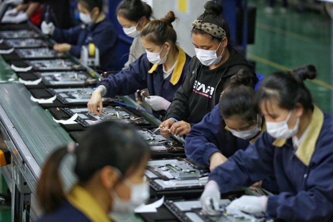 Các nhân viên đeo khẩu trang làm việc trên dây chuyền sản xuất màn hình TV tại nhà máy ở thành phố Vũ Hán, tỉnh Hồ Bắc. Ảnh: TN