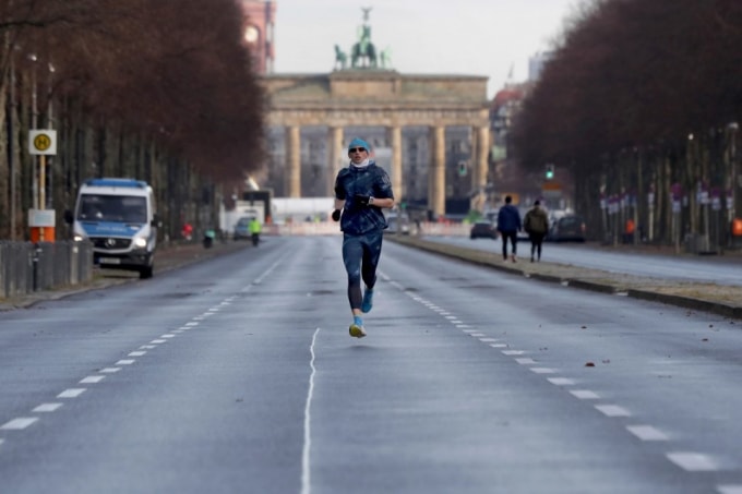 Một người đàn ông chạy trước Cổng Brandenburg ở Berlin, Đức. Do hạn chế của virus corona, các lễ kỷ niệm đêm giao thừa hàng năm tại Cổng Brandenburg với hàng trăm nghìn khách sẽ không diễn ra trong năm nay - Ảnh: Michael Sohn / AP