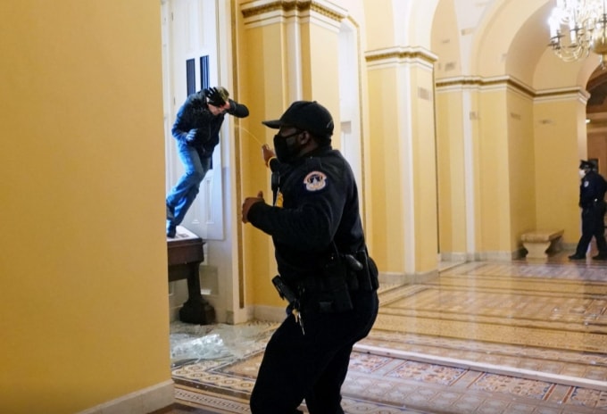 Một người biểu tình ủng hộ ông Trump chèo qua cửa sổ đột nhập vào tòa nhà Quốc hội - Ảnh: Reuters