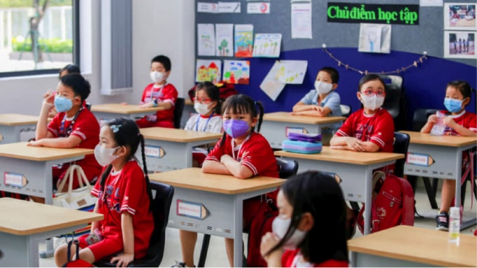 Học sinh tiểu học Việt Nam đeo khẩu trang bảo vệ vào ngày đầu tiên đến lớp sau khi chính phủ nới lỏng lệnh cấm vận trên toàn quốc vào tháng 5 năm 2020. Ảnh: Reuters