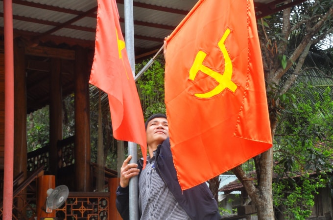 Bí thư Chi bộ bản Ngàm Lương Văn Duẩn đang chỉnh sửa lá cờ cho một hộ dân. Ảnh: Quang Duy
