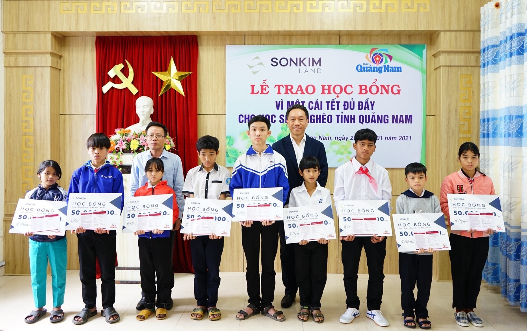 Nhà báo Lê Văn Nhi, Tổng Biên tập Báo Quảng Nam (hàng sau bìa trái) cùng đại diện nhà tài trợ trao học bổng cho các học sinh Ảnh: Xuân Vũ
