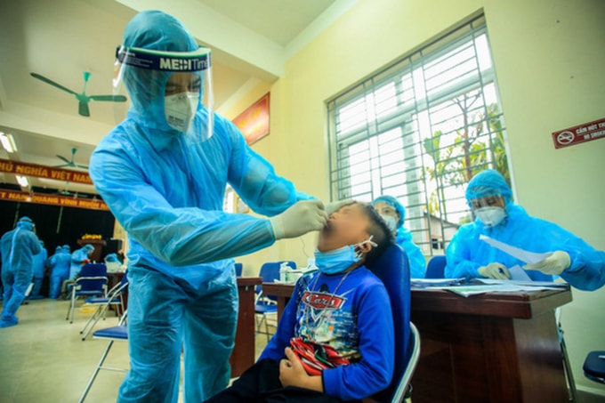 Cán bộ y tế lấy mẫu xét nghiệm cho học sinh Trường Tiểu học Xuân Phương (Ảnh: nguoilaodong)