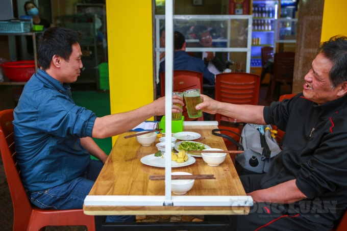 Những ly bia được mọi người cụng nhau qua dưới các tấm kính chắn dịch.