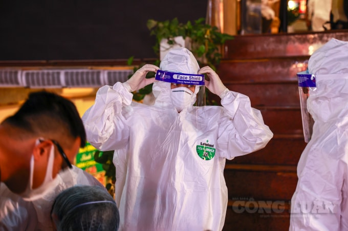Lực lượng chức năng quận Đống Đa thực hiện mặc đồ bảo hộ trước khi tiến hành phun khử khuẩn và lấy mẫu xét nghiệm.
