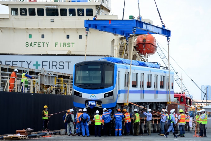 Các kỹ sư, công nhân dùng cẩu tàu có chiều dài 32 m, sức nâng hơn 30 tấn để nâng hạ toa tàu xuống rơ-moóc của xe siêu trường, siêu trọng.