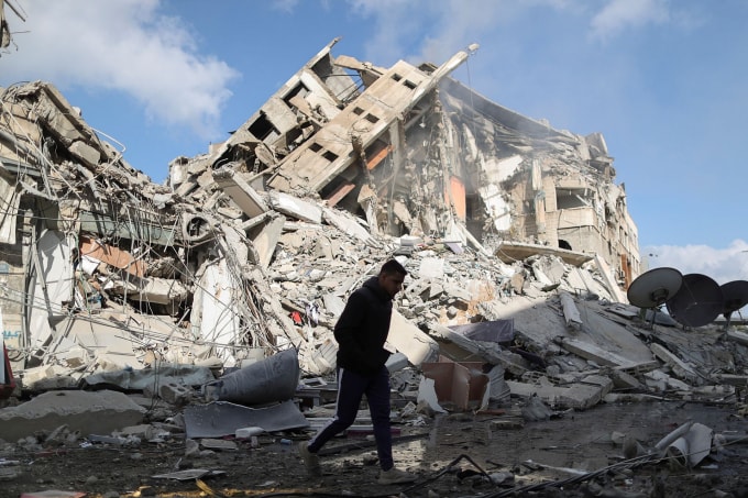 Một người đàn ông Palestine đi ngang qua phần còn lại của một tòa tháp đã bị phá hủy bởi các cuộc không kích của Israel, trong bối cảnh bùng phát bạo lực giữa Israel và Palestine, ở thành phố Gaza ngày 13 tháng 5 năm 2021 - Ảnh: REUTERS / Suhaib Salem