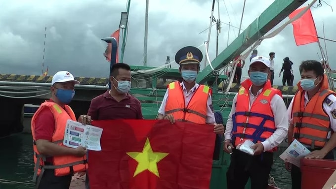 Trao cờ Tổ quốc, khẩu trang y tế và tuyên truyền pháp luật cho ngư dân. Ảnh: NLĐO