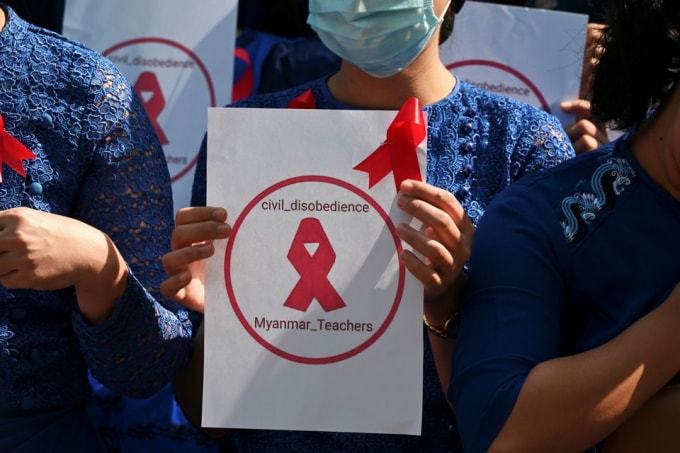 Một giáo viên từ Đại học Sư phạm Yangon cầm một tấm biển với dải băng đỏ khi tham gia biểu tình chống lại cuộc đảo chính quân sự ở Yangon, Myanmar, ngày 5 tháng 2 năm 2021 - Ảnh: REUTERS