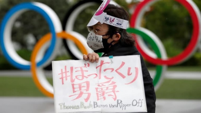 Một người biểu tình giơ tấm biển phản đối Thế vận hội Tokyo - Ảnh: Reuters
