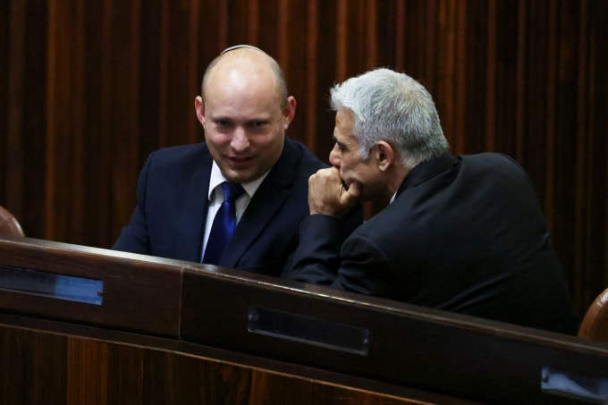 Lãnh đạo đảng Yamina Naftali Bennett (trái) mỉm cười khi nói chuyện với lãnh đạo đảng Yesh Atid Yair Lapid, trong một phiên họp đặc biệt của Knesset - Ảnh: Reuters