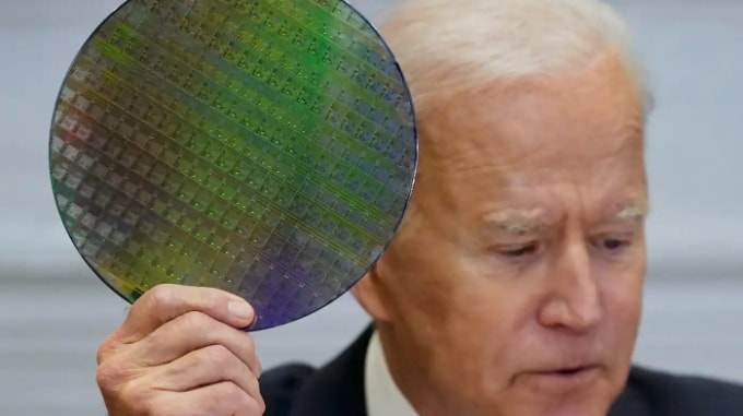 Tổng thống Joe Biden cầm một tấm silicon tại một cuộc họp trực tuyến ngày 12 tháng 4. Sự cạnh tranh ngày càng tăng của Hoa Kỳ với Trung Quốc, kết hợp với tình trạng thiếu chip toàn cầu, đang thúc đẩy Washington củng cố chuỗi cung ứng trong nước. © AP