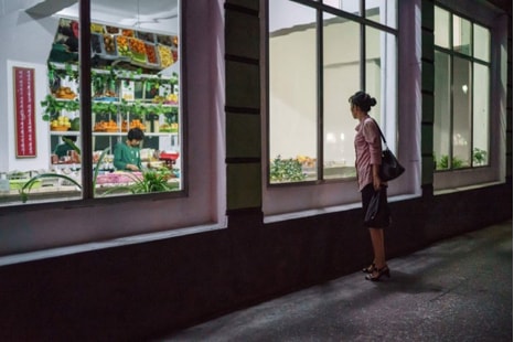 Một phụ nữ đứng bên ngoài cửa hàng tạp hóa trên đường phố ở Bình Nhưỡng. (Nguồn: AFP Photo).