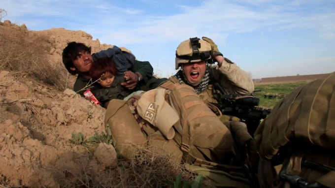 Một lính thủy đánh bộ Mỹ hét lên khi anh ta cố gắng bảo vệ một người đàn ông Afghanistan và đứa con của anh ta sau khi các tay súng Taliban nổ súng ở thị trấn Marjah, thuộc tỉnh Helmand, Afghanistan. © Reuters