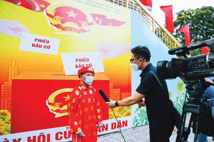 Phóng viên Trần Mộng Long phỏng vấn cử tri trong ngày bầu cử.