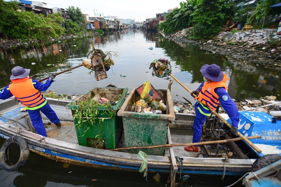 Anh Ngô Tiến Dũng và anh Nguyễn Trung Nguyên dùng vợt vớt rác trên rạch Xuyên Tâm. Ảnh: Lê Phan