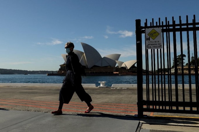 Một người đi bộ đeo khẩu trang đi ngang qua Nhà hát Opera Sydney ở Sydney vào ngày 13/7, trong khi các nhà chức trách tăng cường nỗ lực kiềm chế đợt bùng phát COVID-19 - Ảnh: AFP