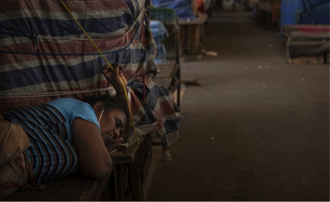 Một người bán rau ở Sri Lanka ngủ bên gian hàng của cô ấy tại một chợ rau bán buôn đã đóng cửa để hạn chế sự lây lan của Covid-19 ở Colombo, Sri Lanka. (Nguồn: Eranga Jayawardena/AP Photo).