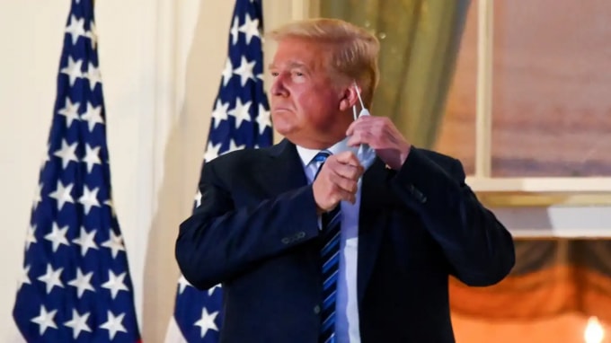 Donald Trump tháo khẩu trang trên ban công của Nhà Trắng sau khi trở về từ bệnh viện sau điều trị COVID. © Reuters
