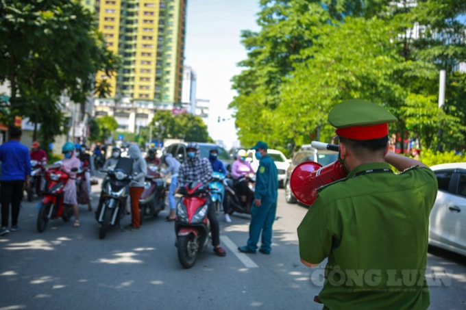 Lực lượng công an phường Ngọc Khánh liên tục loa nhắc nhở người dân xuất trình giấy đi đường ra để kiểm tra.