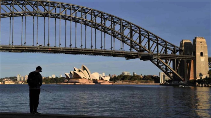 Một người đàn ông đang câu cá tại bến cảng từ Nhà hát Opera Sydney. Cư dân và các cơ sở kinh doanh ở khu vực Sydney rộng lớn hơn đang bị hạn chế chặt chẽ về COVID-19. Ảnh: Getty Images.