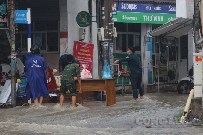 Lực lượng trực chốt kiểm soát dịch bệnh Covid-19 phải sơ tán tìm nơi trú mưa.