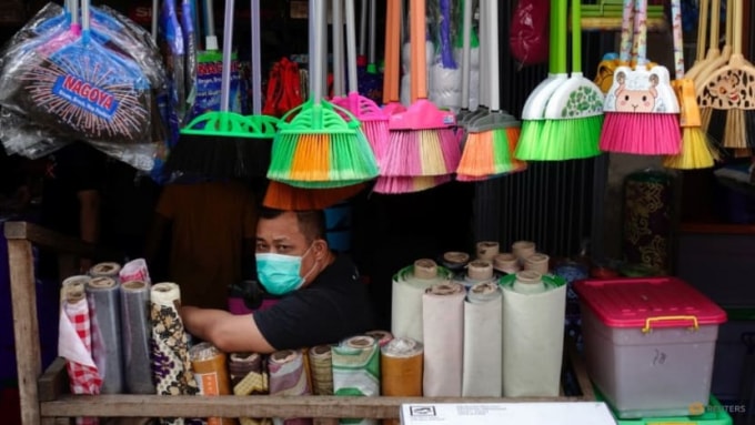 Một tiểu thương trước cửa hàng ế ẩm do vắng khách vì các hạn chế COVID-19 kéo dài tại Jakarta, Indonesia - Ảnh: Reuters