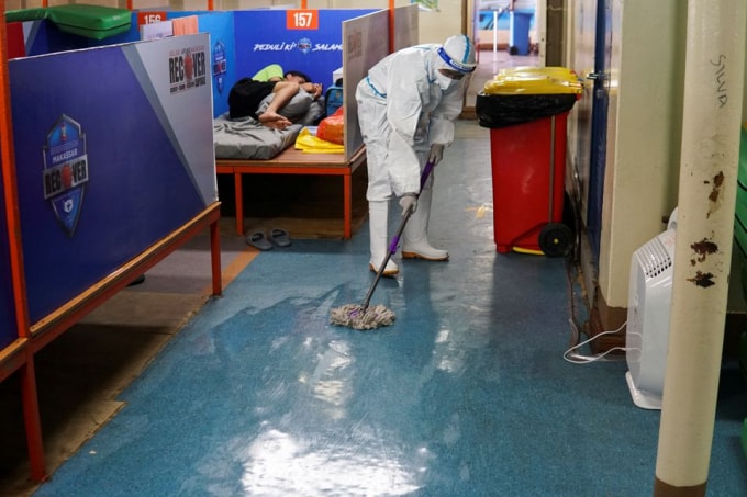 Một nhân viên mặc thiết bị bảo hộ cá nhân (PPE) khử trùng sàn trên boong của một con tàu chở khách, thuộc sở hữu của công ty vận tải quốc doanh PT PELNI, KM Umsini, Indonesia - Ảnh: Reuters