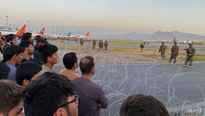 Đám đông người Afghanistan tại sân bay Kabul muốn rời khỏi đất nước trong khi nhiều lính Mỹ đứng gác đảm bảo an ninh vào ngày 16 tháng 8 năm 2021 - Ảnh: Shakib Rahmani / AFP