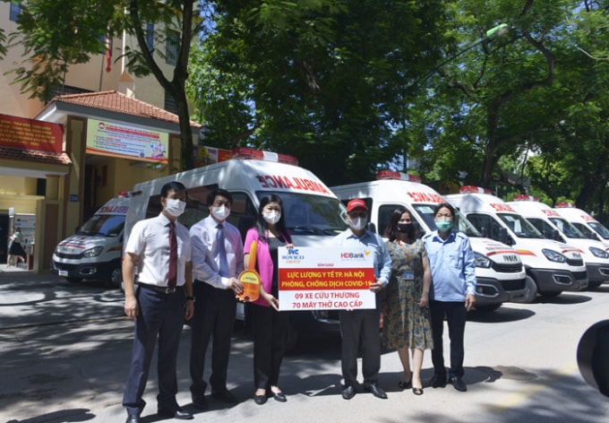Chủ tịch Ủy ban MTTQ TP Nguyễn Lan Hương tiếp nhận xe cứu thương và máy thở từ các đơn vị. Ảnh: HNP
