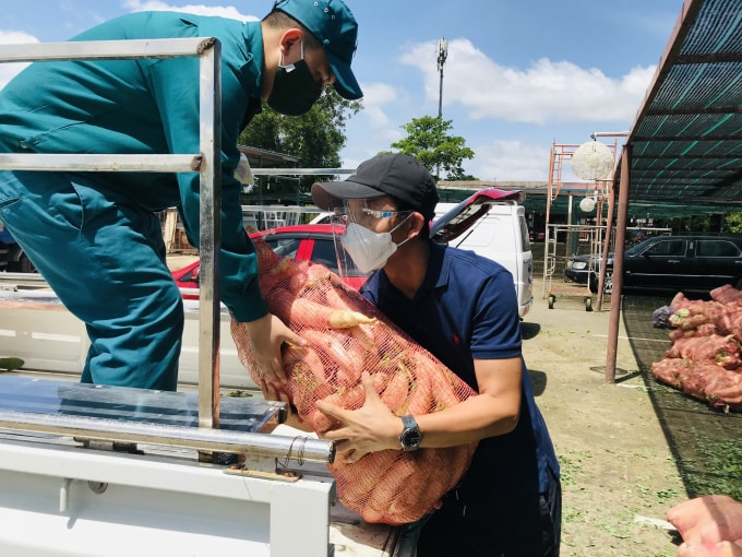 Nhà báo Nguyễn Đình Sơn (người bên trái) đang bốc vác rau củ lên xe để chuyển đến các địa điểm cần giúp đỡ.