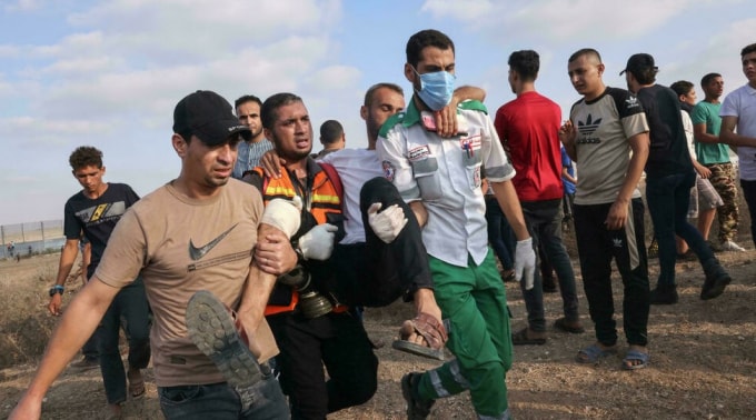 Các nhân viên y tế và người biểu tình Palestine sơ tán một người đàn ông bị thương trong cuộc đụng độ với lực lượng an ninh Israel hôm thứ Bảy - Ảnh: AFP