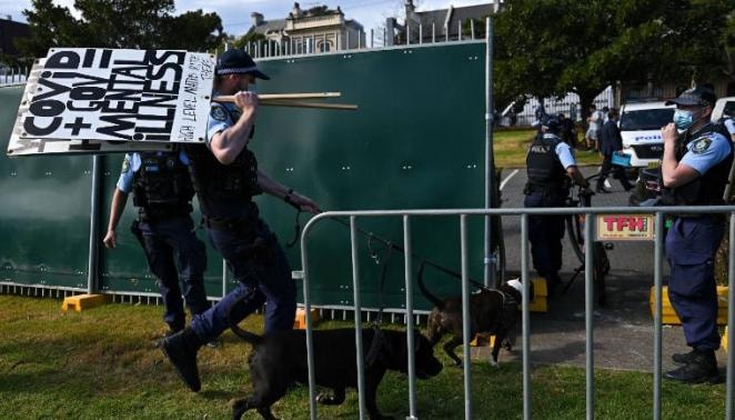 Một sĩ quan cảnh sát tịch thu biểu ngữ trong cuộc biểu tình ở Sydney, Australia, vào ngày 21 tháng 8. Ảnh: CNN