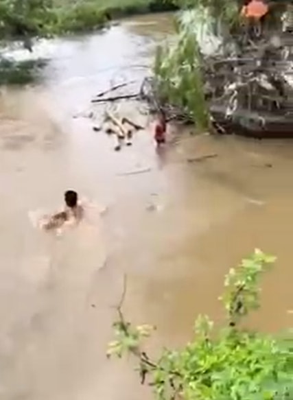 Anh Chu Quang Sao không ngần ngại lao xuống dòng nước dữ để giải cứu cháu bé. Ảnh cắt từ clip