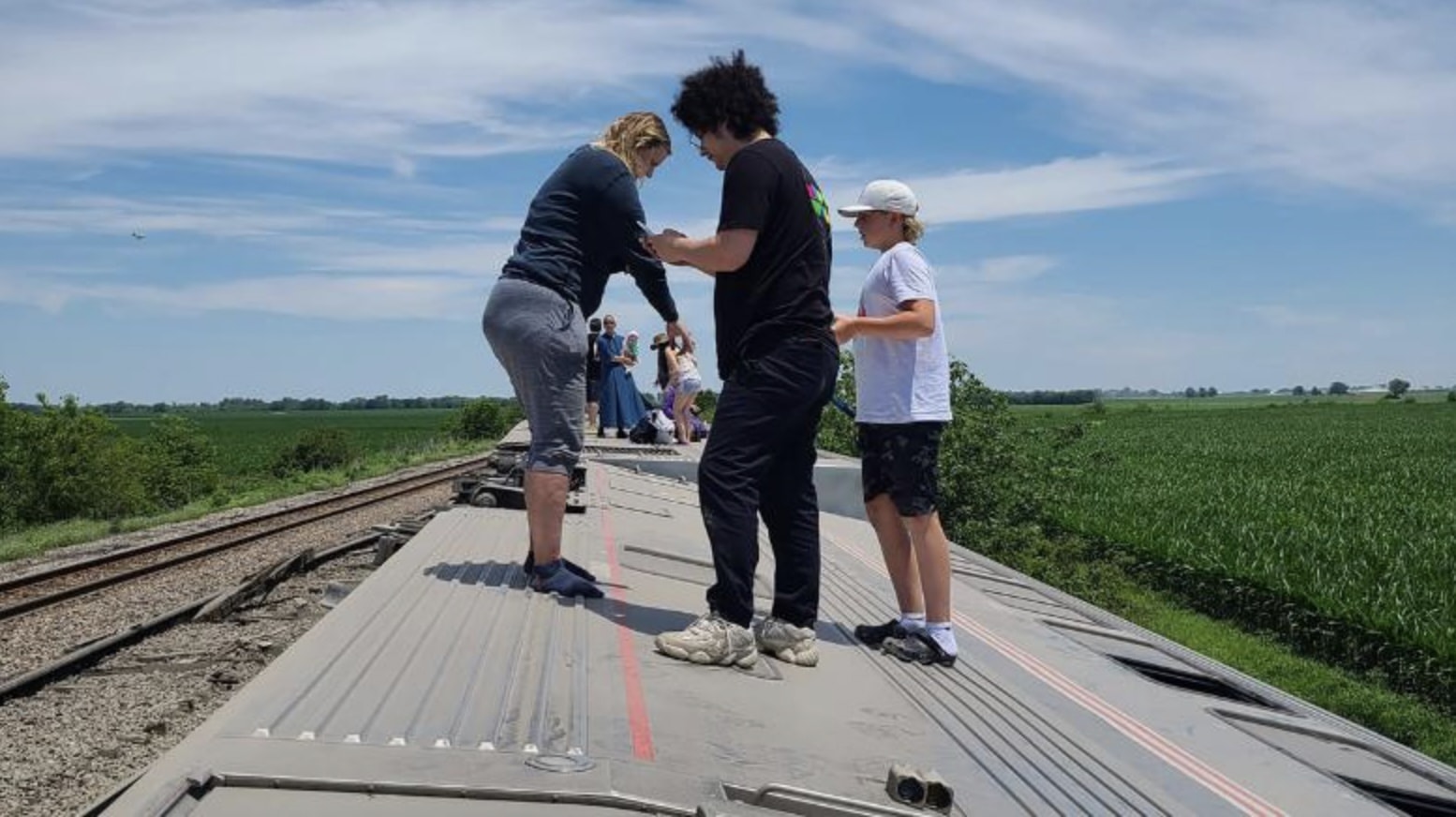 Mọi người đứng trên thành tàu Amtrak bị lật ở Mendon, Missouri. Ảnh: CNN