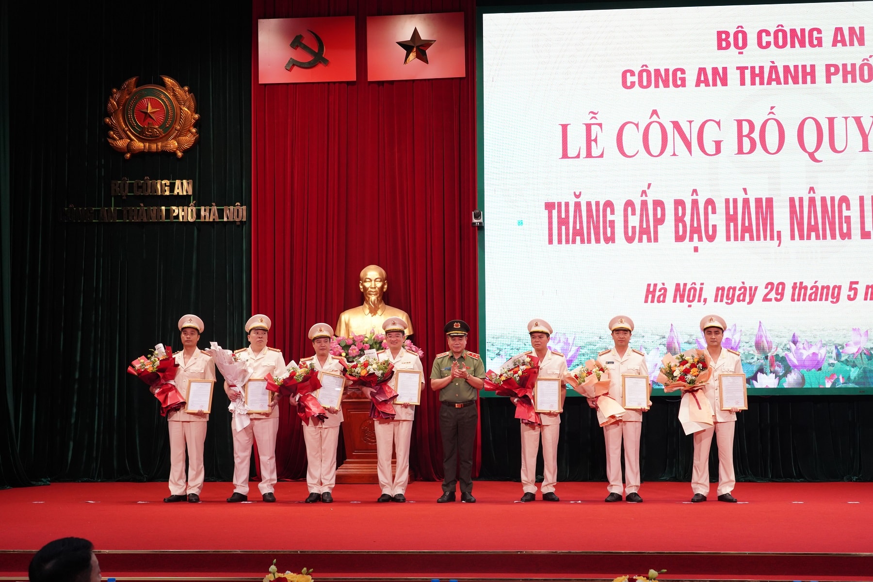 Trung tướng Nguyễn Thanh Tùng, Giám đốc CATP trao quyết định, tặng hoa chúc mừng các đồng chí được thăng cấp bậc hàm lên Đại tá. Ảnh: CAH