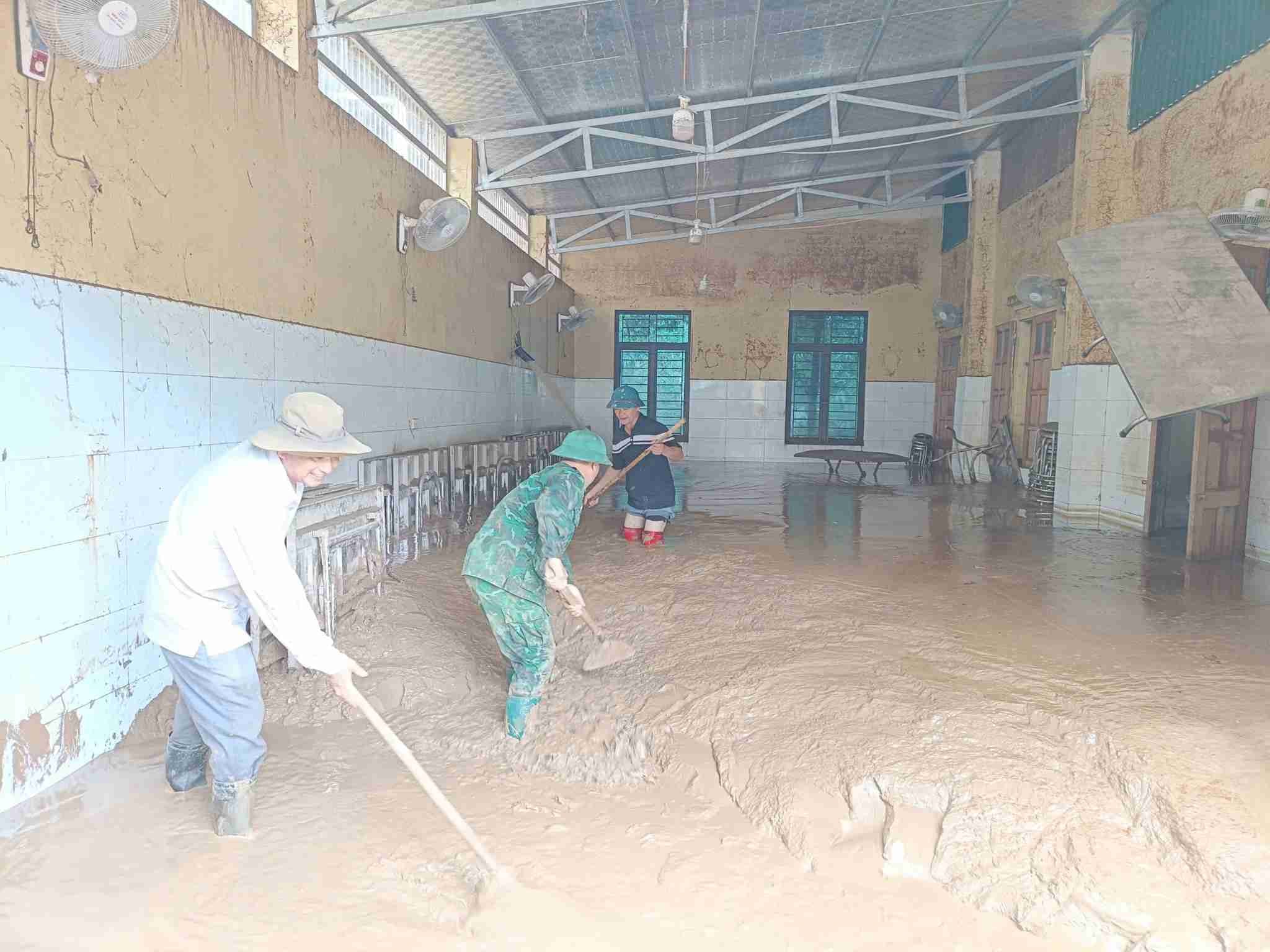 Bộ đội, giáo viên vật lộn với khối lượng bùn khổng lồ trong các phòng học. Ảnh: Gia Thảo